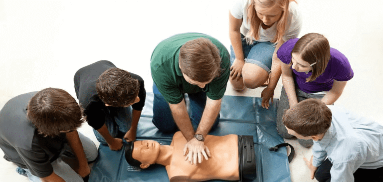 Instructor teaching CPR to students using a manikin.