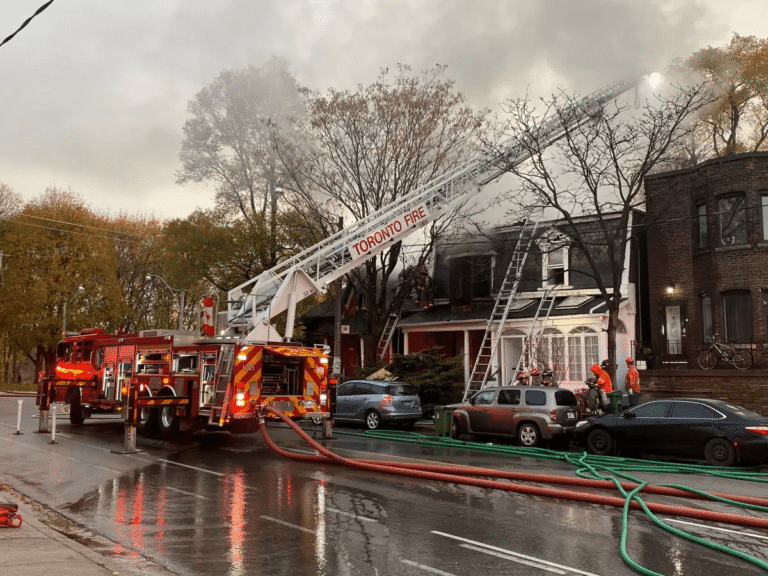 Toronto Fire crews using ladder trucks and hoses to battle a house fire on a residential street in Scarborough.