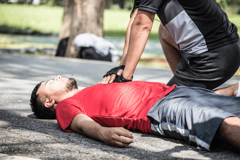 Bystander performing CPR chest compressions on an unconscious man after sudden cardiac arrest.
