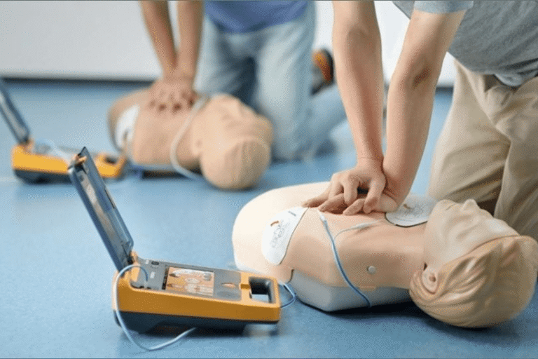 Students practicing CPR and AED use on training manikins during a first aid course.