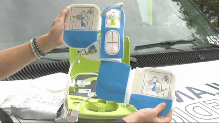 A paramedic demonstrating how to use a public access defibrillator (AED) with illustrated electrode pads.