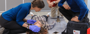 First aid instructor performing an emergency assessment during CPR training, demonstrating lifesaving skills similar to those used by a constable who revived a newborn.