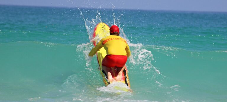 Surfer assisting another person in the water during an emergency near the shoreline.